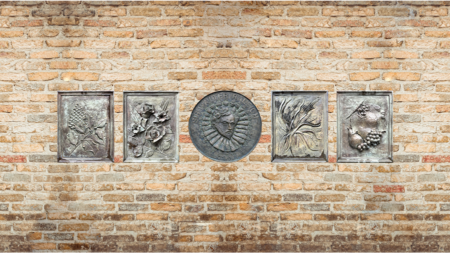 Five decorative bronze plaques displayed against a brick wall background at the Sandhills Community College Horticultural Gardens, featuring floral and agricultural relief designs.