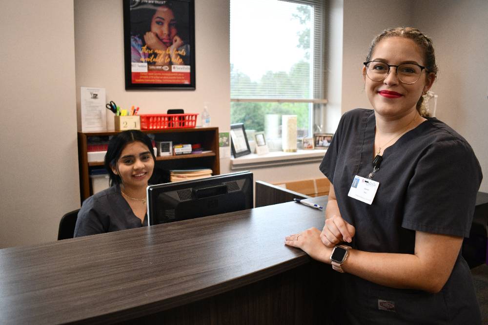 two medical students smiling at front desk