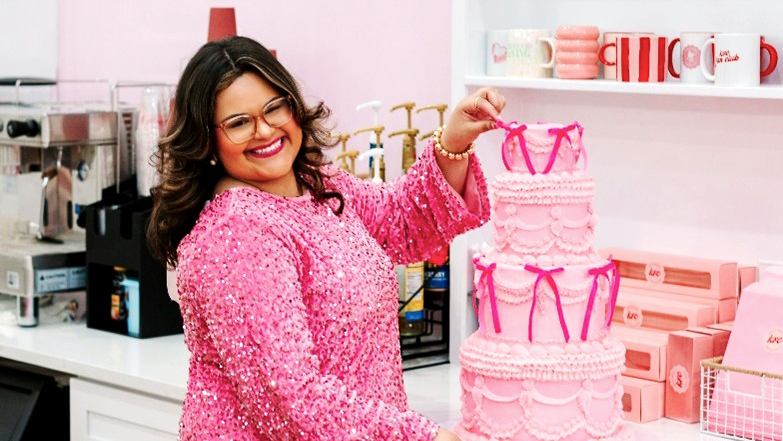 Kayla Renee, owner of Kayla Renee Cakes, poses with a custom pink tiered cake inside her Raeford bakery.