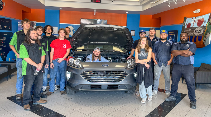 SCC Collision Repair students gather around a modified Ford Escape in the automotive lab.