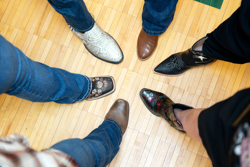 Close-up of five people wearing colorful cowboy boots in a circle on the gym floor during an SCC Personal Enrichment dance class.