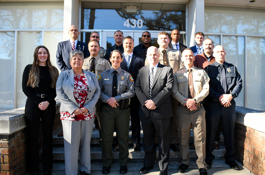 Graduates of the Sandhills Community College Basic Law Enforcement Training Academy stand with faculty outside a campus building.