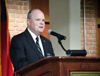 BLET Director Ron Turk speaks at a podium during a graduation ceremony at Sandhills Community College.