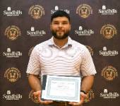 Student Matthew Goodwin holding an award certificate and smiling in front of a Sandhills Community College Student Awards Day backdrop.