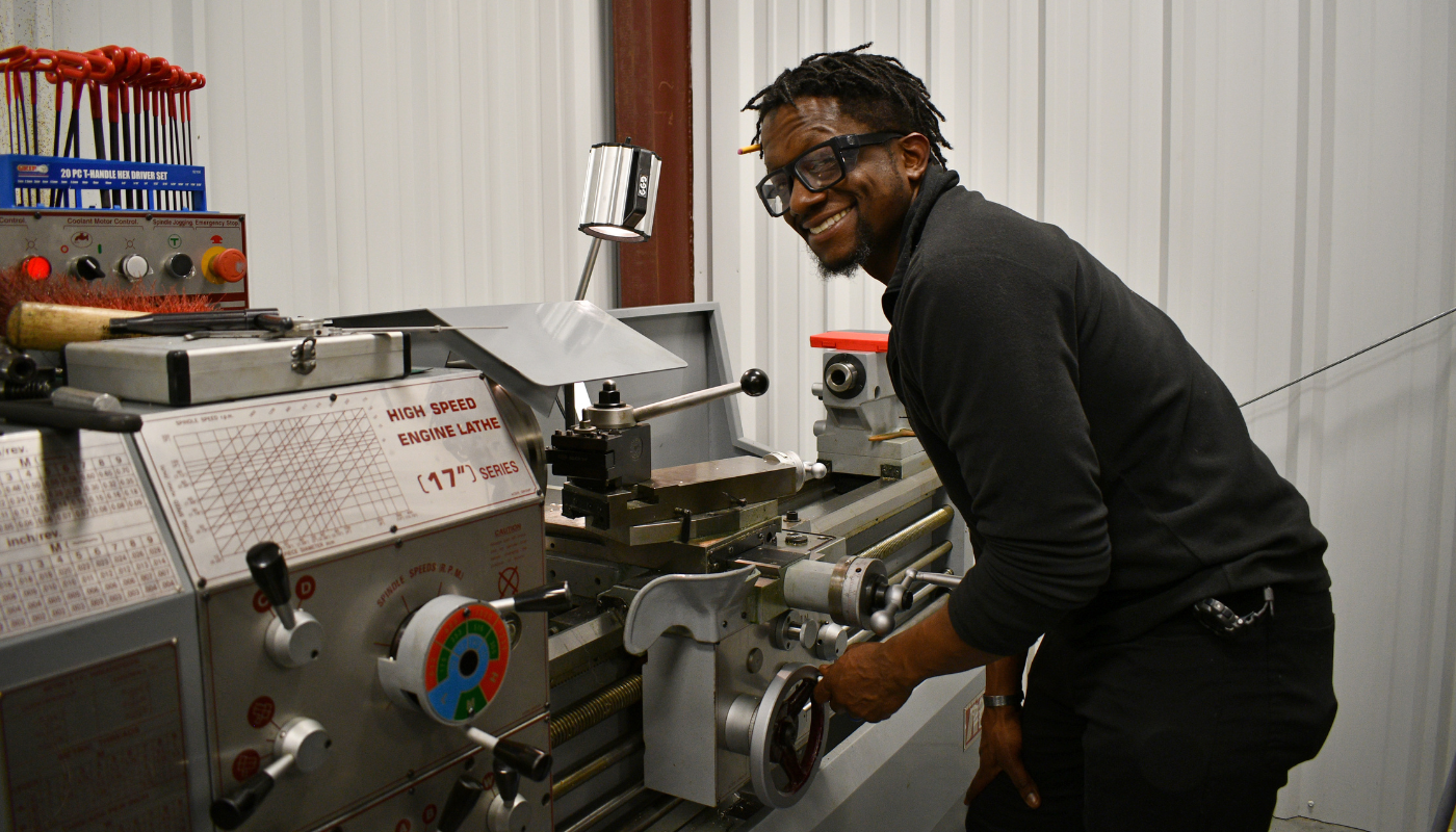 Pictured is a man working on a CNC machine. 