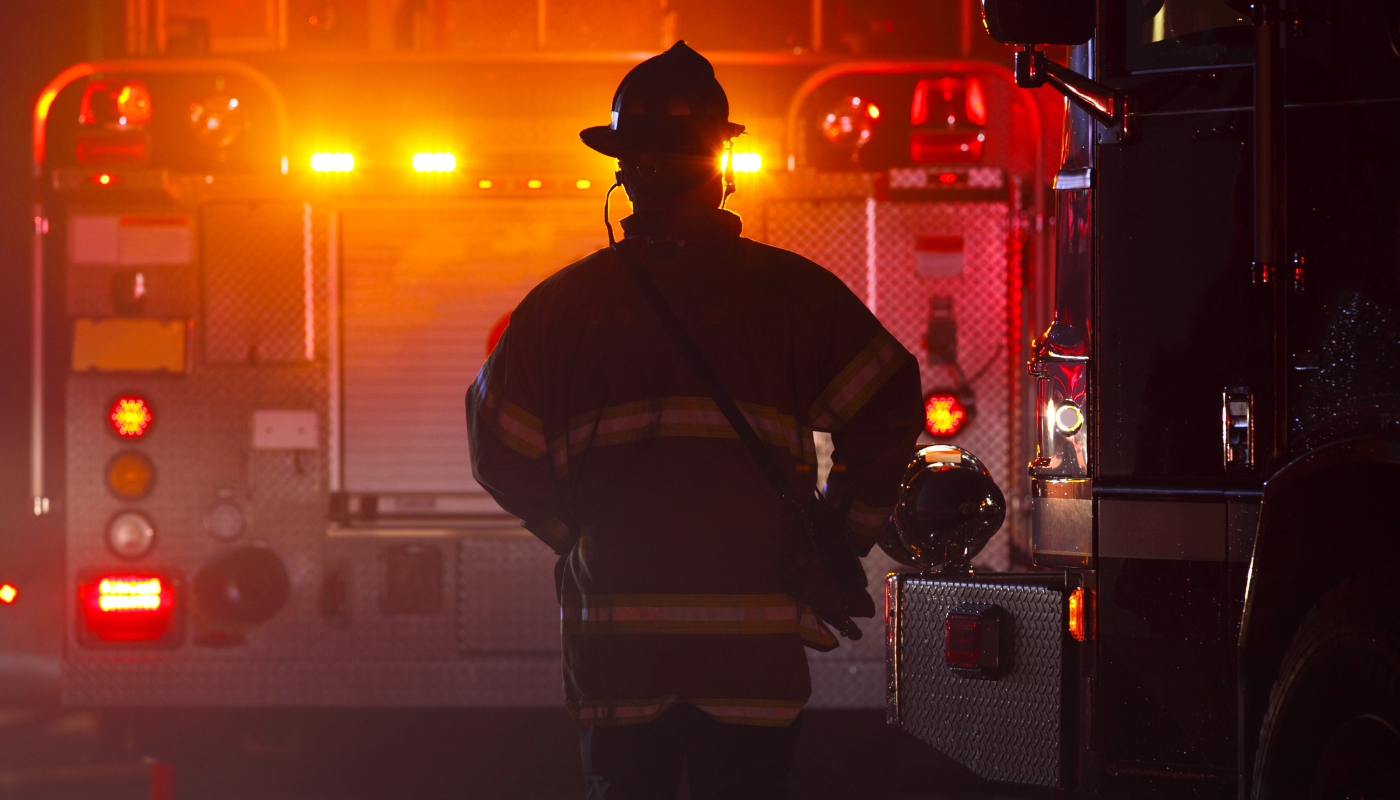 Pictured is a fire fighter at the back of a fire truck.