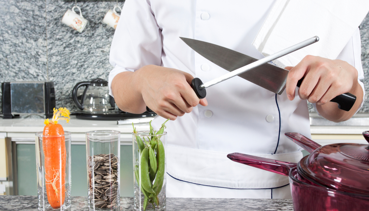 A chef is sharpening a knife in a kitchen.