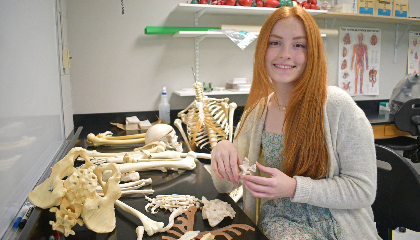 Mackenzie Peden is pictured in a science lab holding bones. 