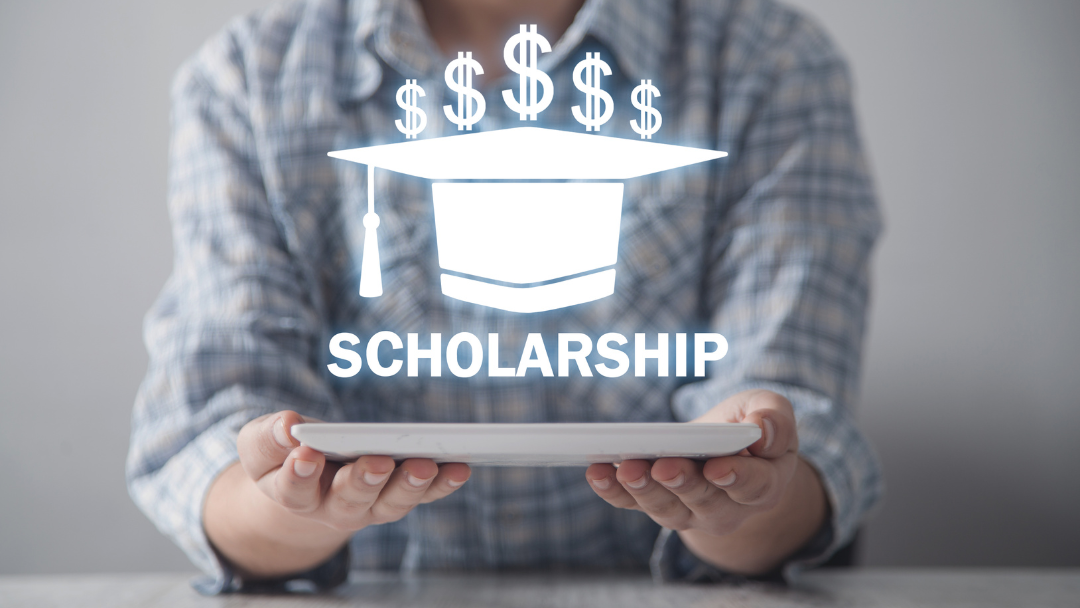 Pictured are hands holding a tablet, and hovering above it is a graduation cap, dollar signs, and the word "scholarship."