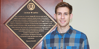 Matthew Pittman poses for a photo in front of a plaque.