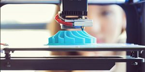 Close up of a 3D printing machine, making a blue object.