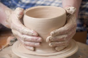 Hands of a potter, creating an earthen jar on the circle.