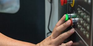 Student pushes a green button on a piece of machinery.