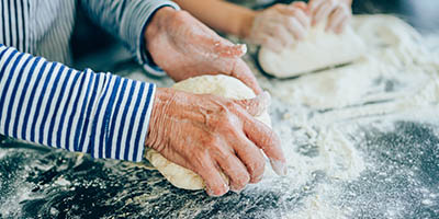 Close up of four hands working with bread dough.
