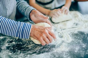 Close up of four hands working with bread dough.