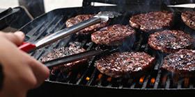 Close up of hamburgers cooking on a grill.