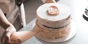 Close up of a person piping icing on to a cake.